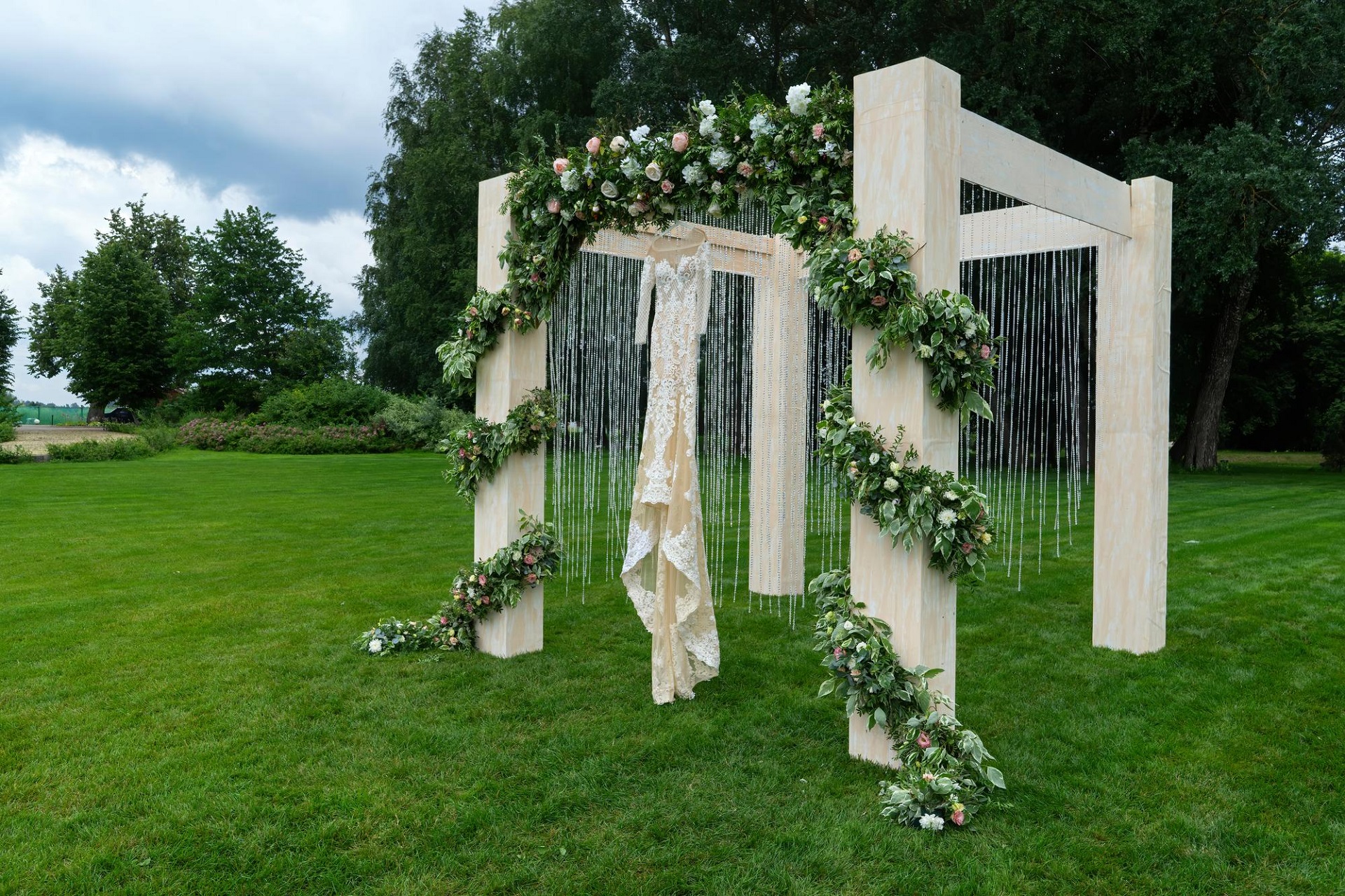 outdoor-wedding-park-beautiful-dress-is-hanging-wedding-arch-diagonal-view1.